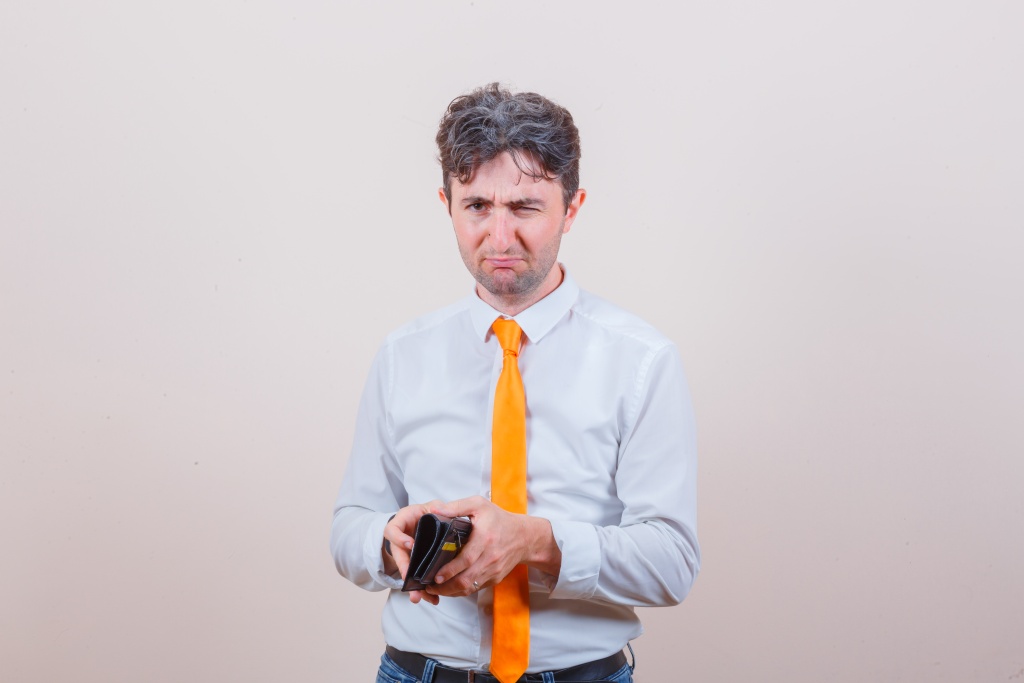 young-man-holding-wallet-shirt-tie-jeans-looking-pensive.jpg кошелек